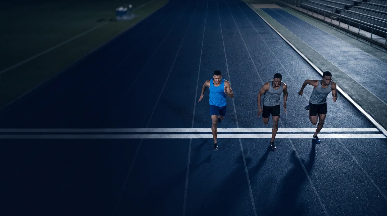 Three sprinters cross a finish line nearly shoulder to shoulder on a dark track, the runner in blue just ahead, like Gemini 4 Argon edging its two closest rivals.